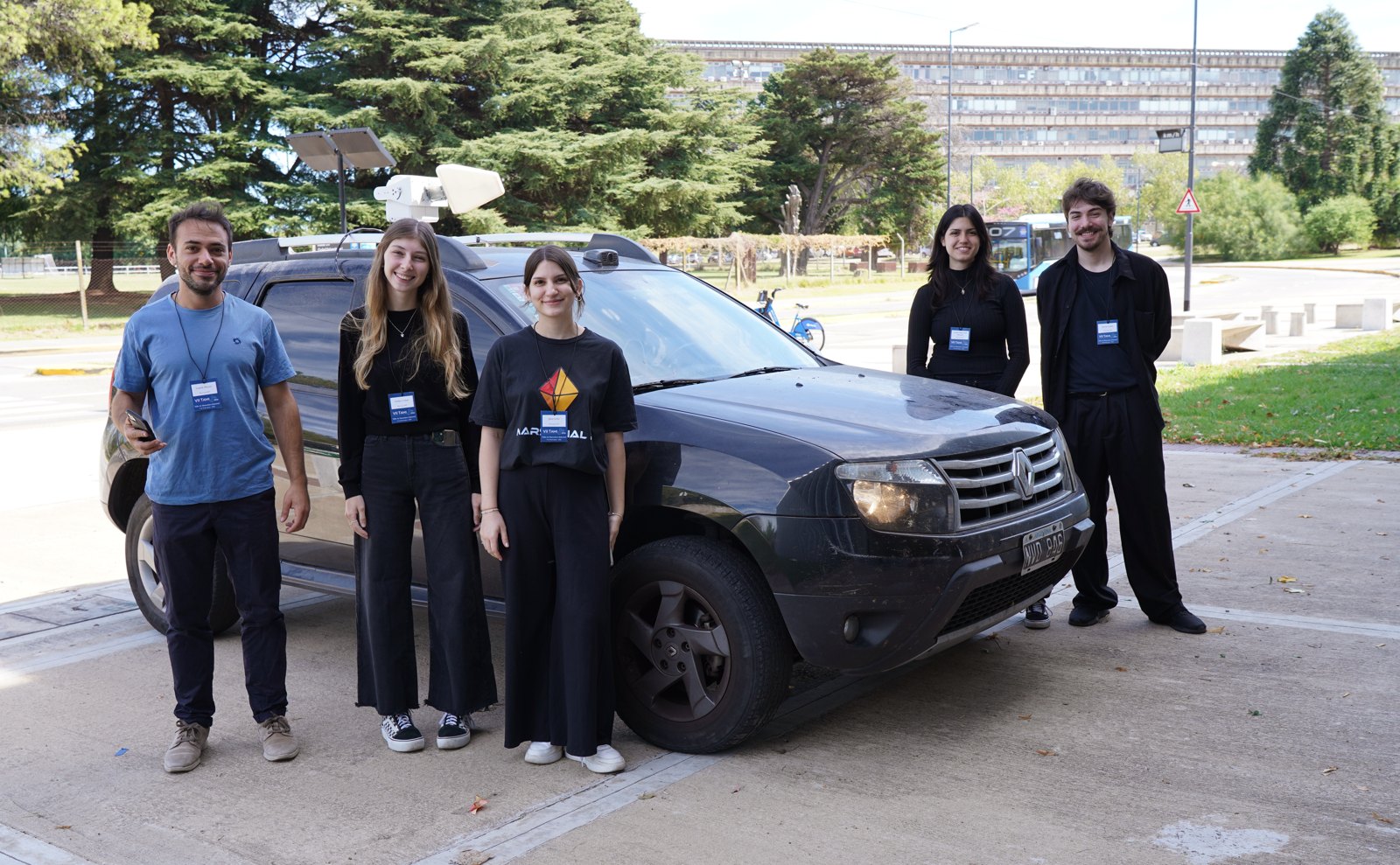 Marsupial RF team standing next to a test vehicle with roof-mounted equipment.